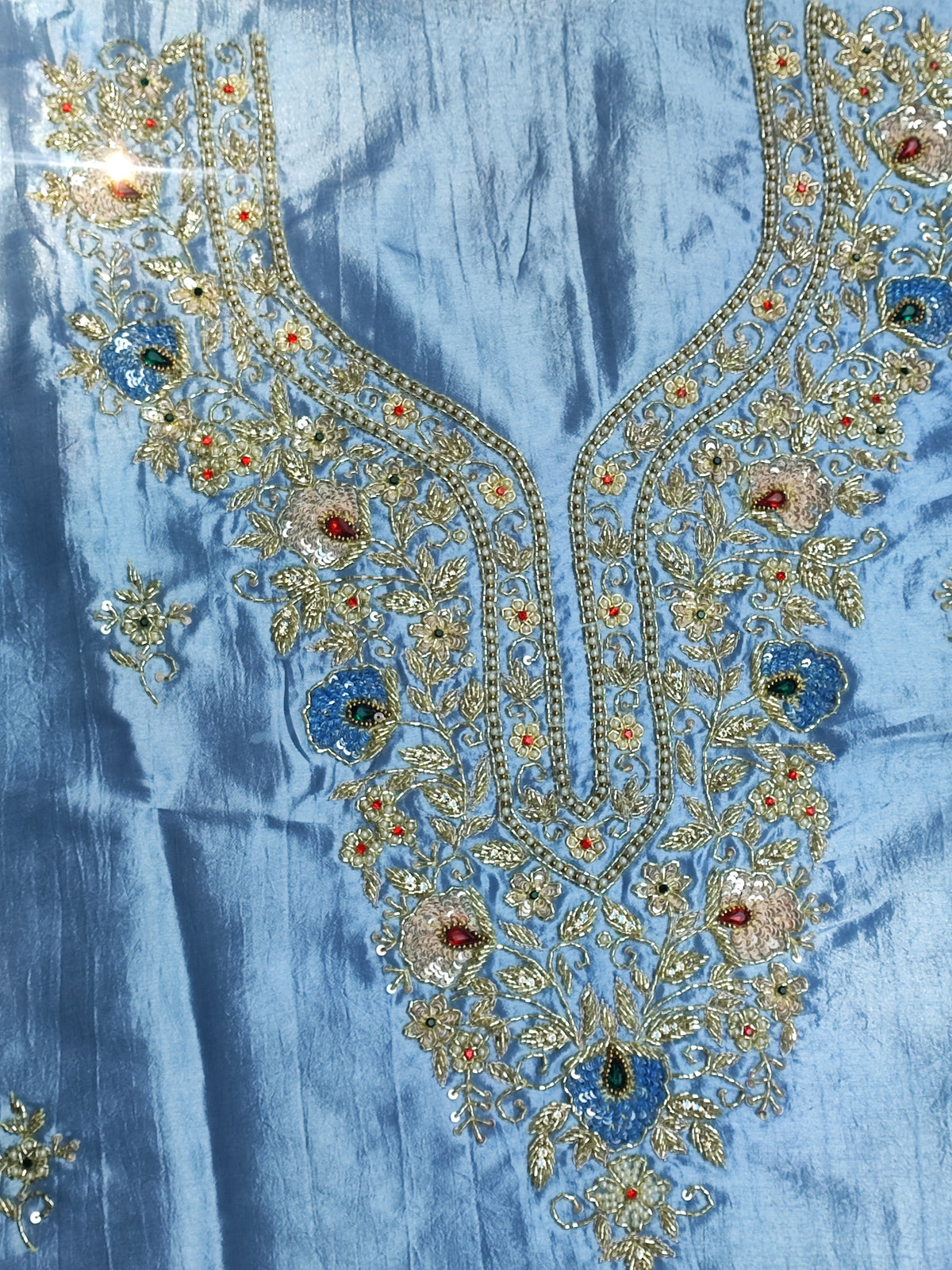 Close-up of hand embroidery with stone, pearl, sippi and katdana work on blue silk